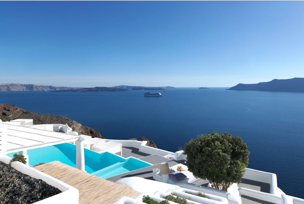 Luxurious white-washed cliffside hotel in Santorini featuring private infinity pools and curved balconies overlooking the Aegean Sea