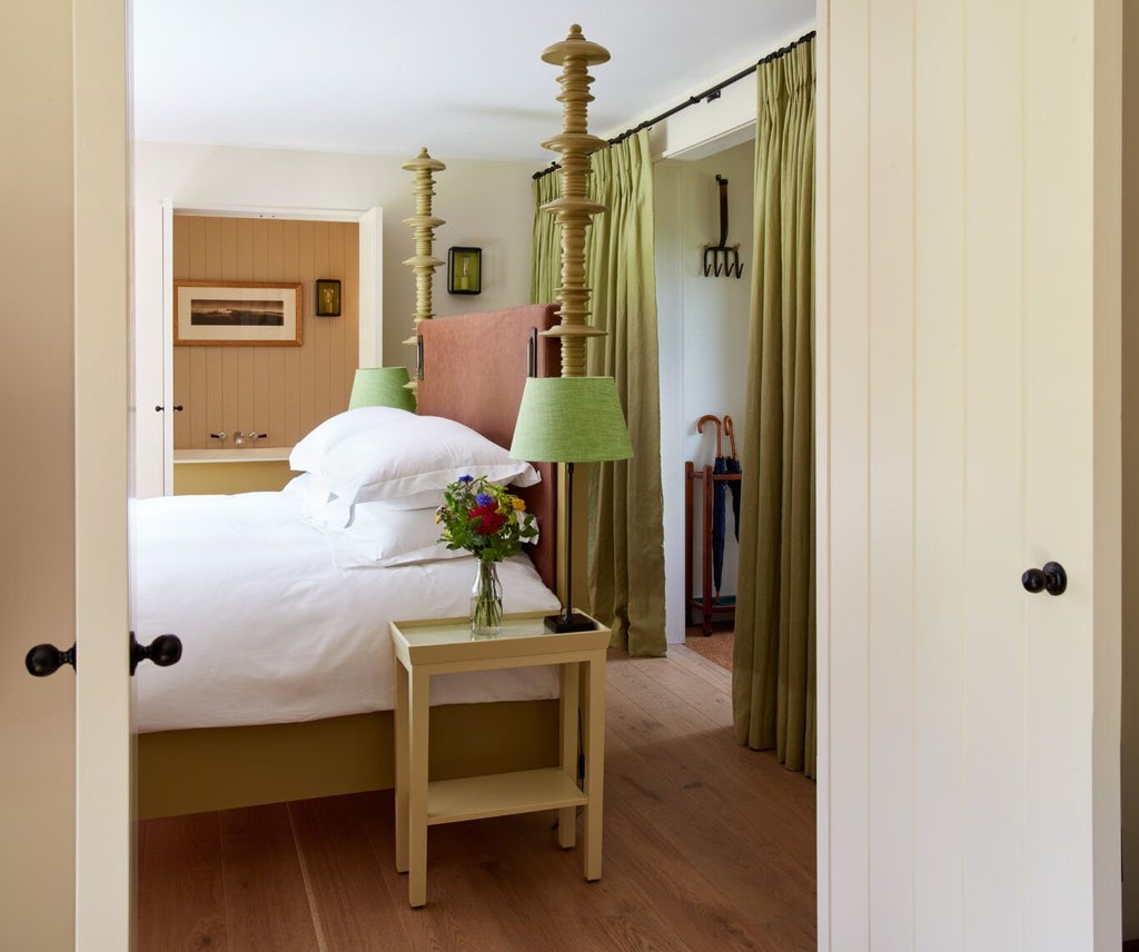 Elegant boutique hotel room with soft neutral tones, plush white bedding, rustic wooden furniture, and warm lighting at Grove of Narberth's Lovage suite