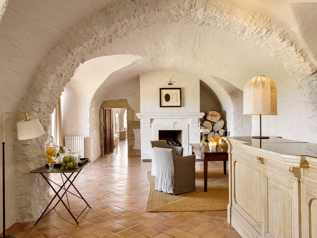 Elegant Spanish manor hotel with stone walls, arched windows and terracotta roof, surrounded by manicured gardens and cypress trees