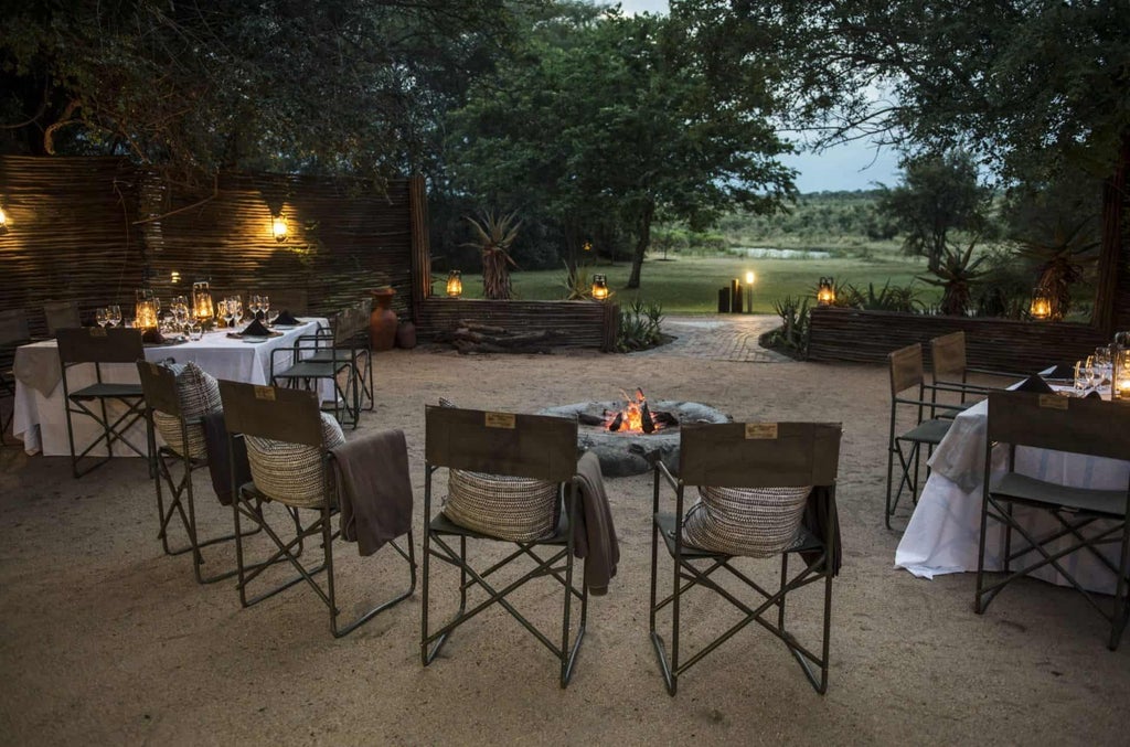 Luxurious African safari lodge with thatched roof and wrap-around wooden deck overlooking a vast savanna at golden hour