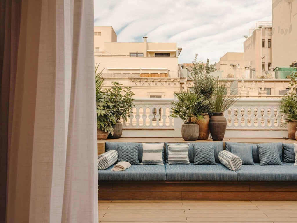 Elegant Pulitzer Suite in Barcelona, featuring plush white bed, modern design, and private terrace with city view and warm afternoon sunlight