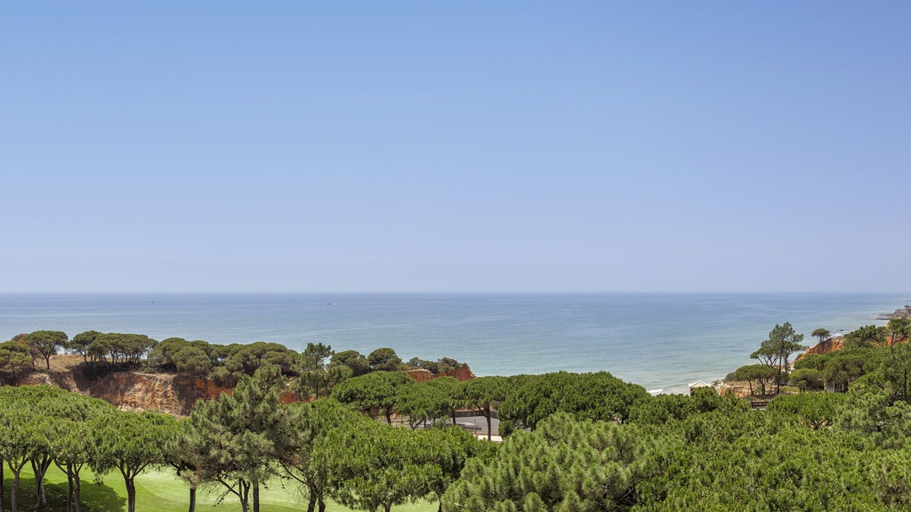 Luxurious seaside resort with white Mediterranean architecture nestled among pine trees overlooking Portugal's red-cliffed coastline