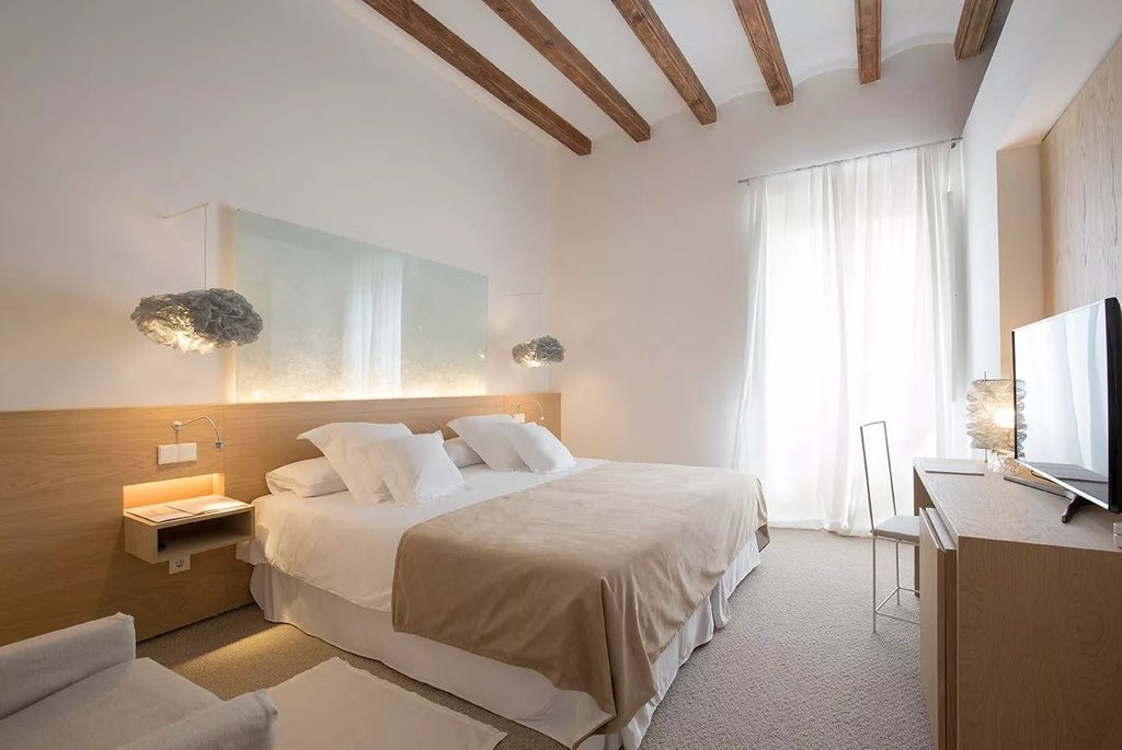 Elegant stone-walled deluxe hotel room with contemporary furnishings, plush white bedding, and warm mood lighting in historic Missió hotel, Spain