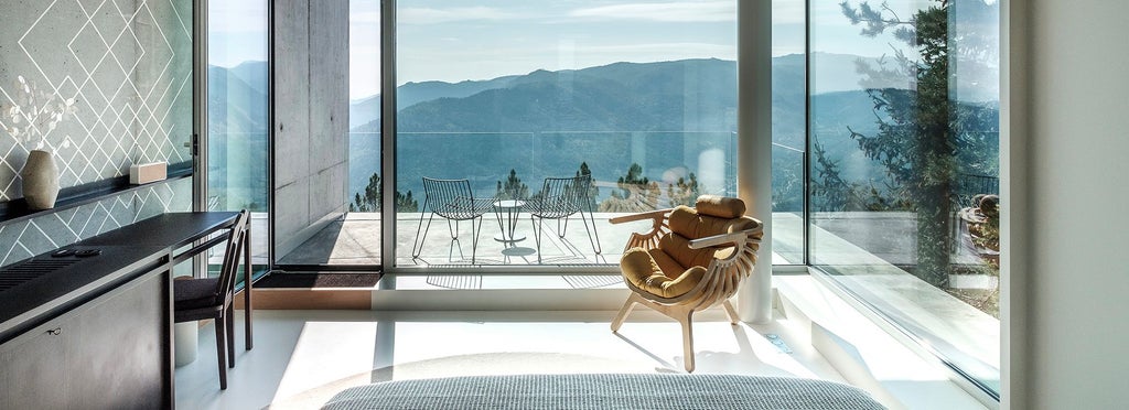 Luxurious hotel room with panoramic mountain views, featuring contemporary Portuguese design, elegant furnishings, and expansive windows at Casa de São Lourenço