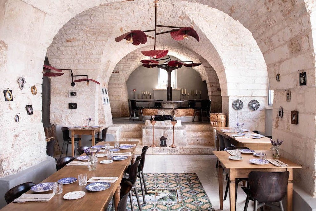 Opulent Baroque-style boutique hotel in Puglia, Italy, with striking red facade, elegant architecture, and lush Mediterranean garden setting