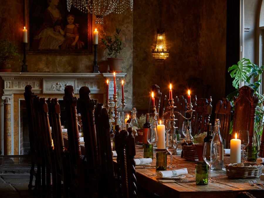 Historic stone-walled boutique hotel room with rustic luxe decor, plush bedding, antique furniture, and warm ambient lighting in a charming UK setting