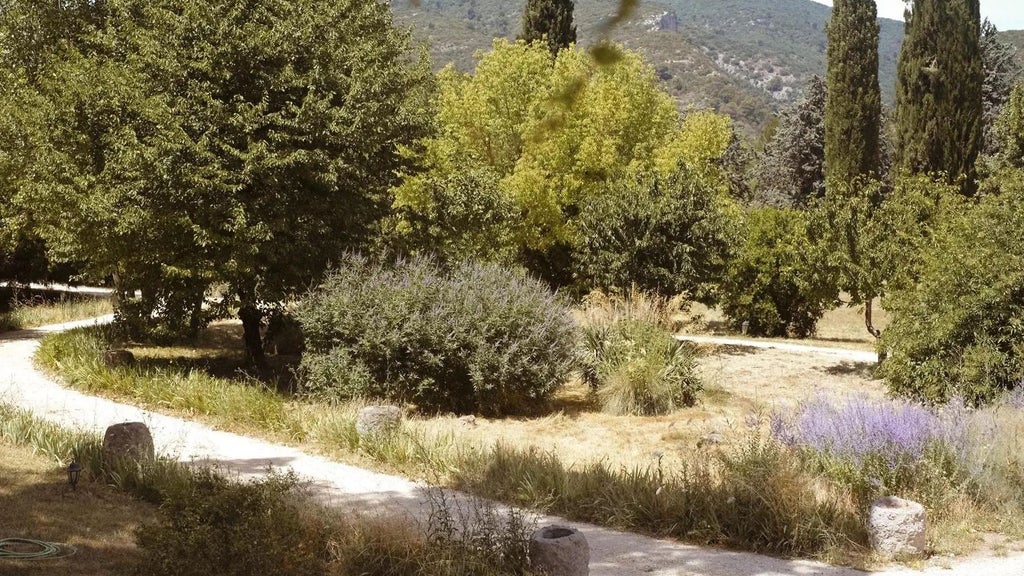 Elegant stone facade of Le Galinier boutique hotel in Provence, featuring rustic terracotta roof, lavender-lined courtyard, and soft afternoon sunlight.