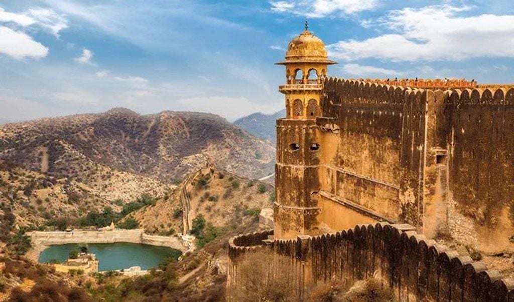 Opulent Indian hotel with grand Mughal-style domes, surrounded by lush gardens, reflecting pools and traditional pink sandstone architecture