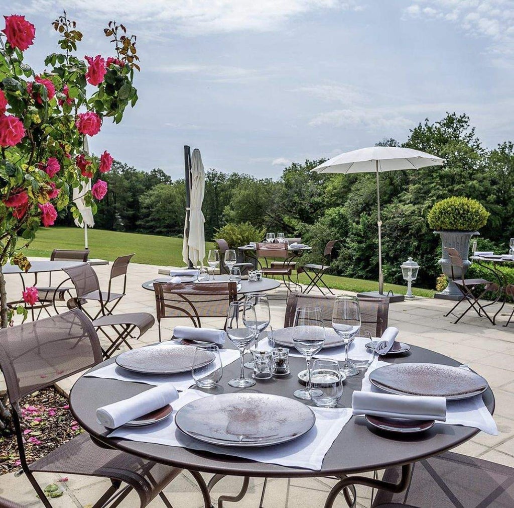 French chateau-style hotel with elegant stone facade, ivy-covered walls, and manicured gardens set against a backdrop of rolling countryside