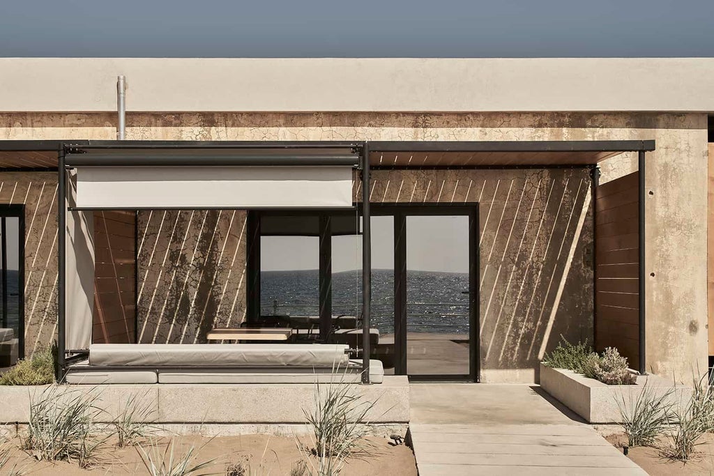 Minimalist beachfront suite converted from wine tank at Dexamenes Hotel, featuring sleek concrete design with panoramic Aegean Sea view and rustic elegance