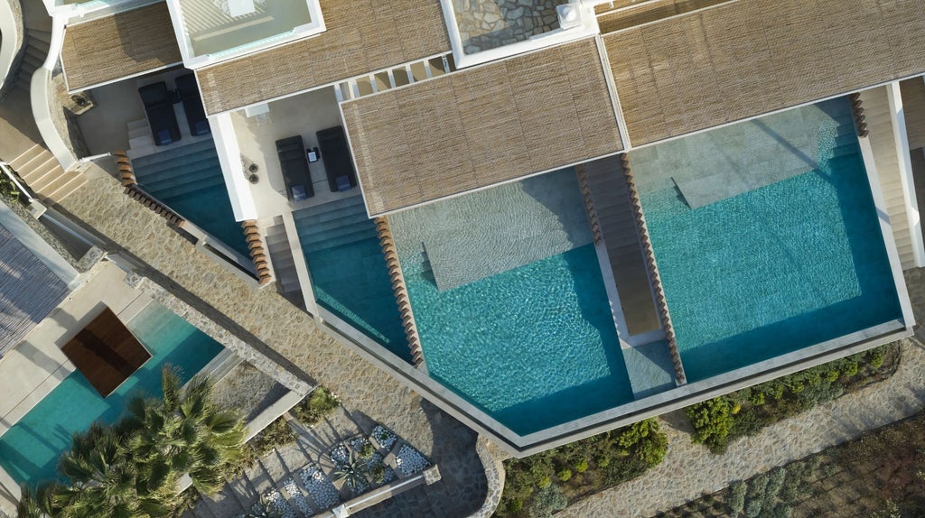 Elegant beachfront suite with private infinity pool overlooking the Aegean Sea, featuring minimalist white architecture at sunset