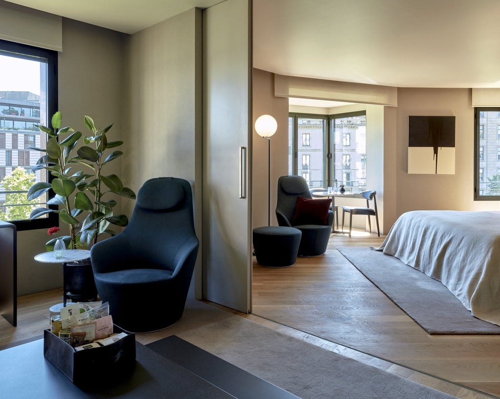 Luxurious modern hotel suite with sleek design, large windows overlooking urban scenery, minimalist furniture, and sophisticated monochromatic color palette in Barcelona