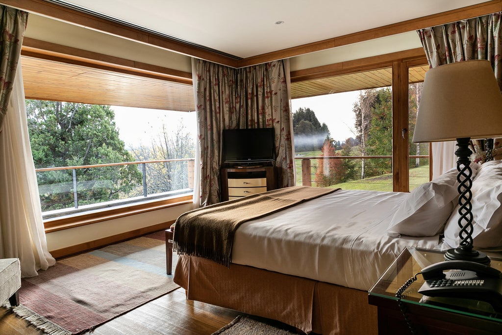 Luxurious Alpine-style hotel with steep green roofs nestled between snow-capped mountains and blue lakes in Patagonian wilderness