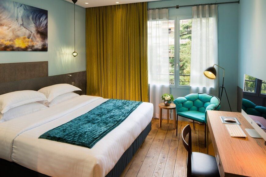 Elegant garden-view deluxe room with plush white bedding, soft green accents, and French-inspired decor at Hotel & Spa La Belle Juliette in Paris