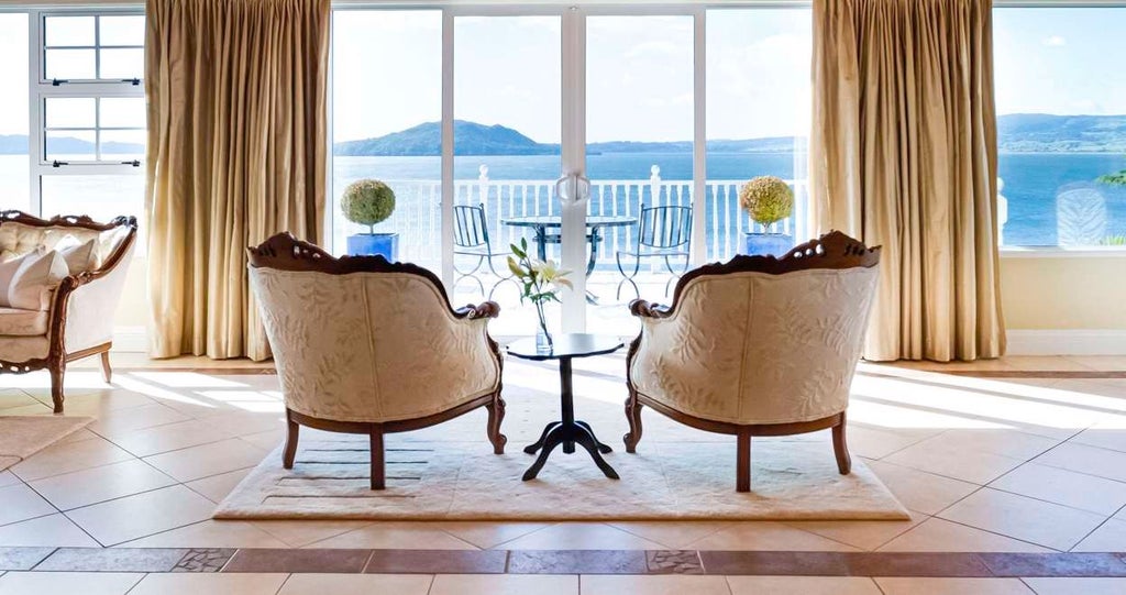 Luxurious main suite with panoramic lake views, elegant contemporary design, plush king bed, and floor-to-ceiling windows showcasing scenic New Zealand landscape