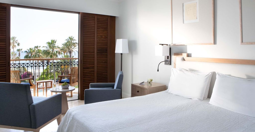 Elegant sea view room with plush white bedding, modern minimalist design, and panoramic azure Mediterranean waters through floor-to-ceiling windows