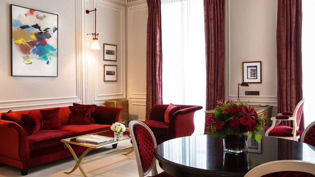 Elegant Parisian luxury suite with plush cream-colored furniture, rich wood accents, and expansive city view through floor-to-ceiling windows at prestigious hotel