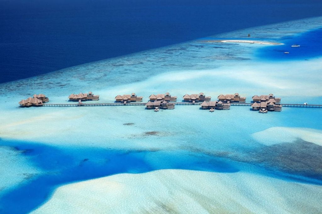 Luxurious overwater villa with wooden walkway at Gili Lankanfushi resort, surrounded by crystal-clear turquoise Maldivian waters