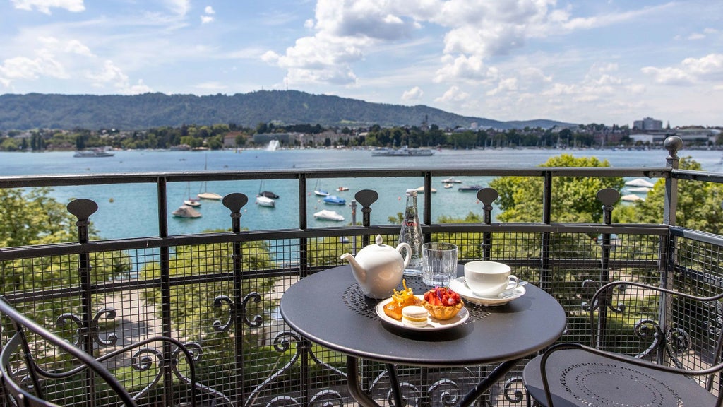 Luxurious lakeside hotel with panoramic views of Zurich's azure waters, elegant Art Nouveau architecture, and pristine white exterior against Alpine landscape