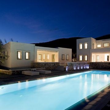 Luxurious white-washed Greek hotel nestled on Sifnos island, featuring minimalist architecture, infinity pool overlooking azure Aegean Sea at sunset