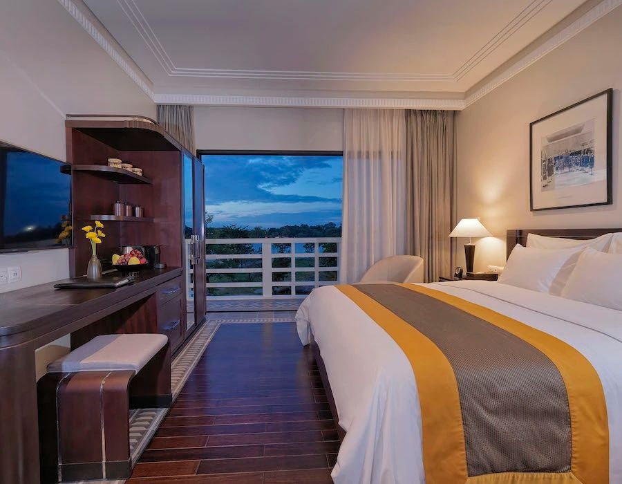 Elegant Vietnamese hotel room with French colonial design, river view, polished hardwood floors, white linens, and traditional architectural details