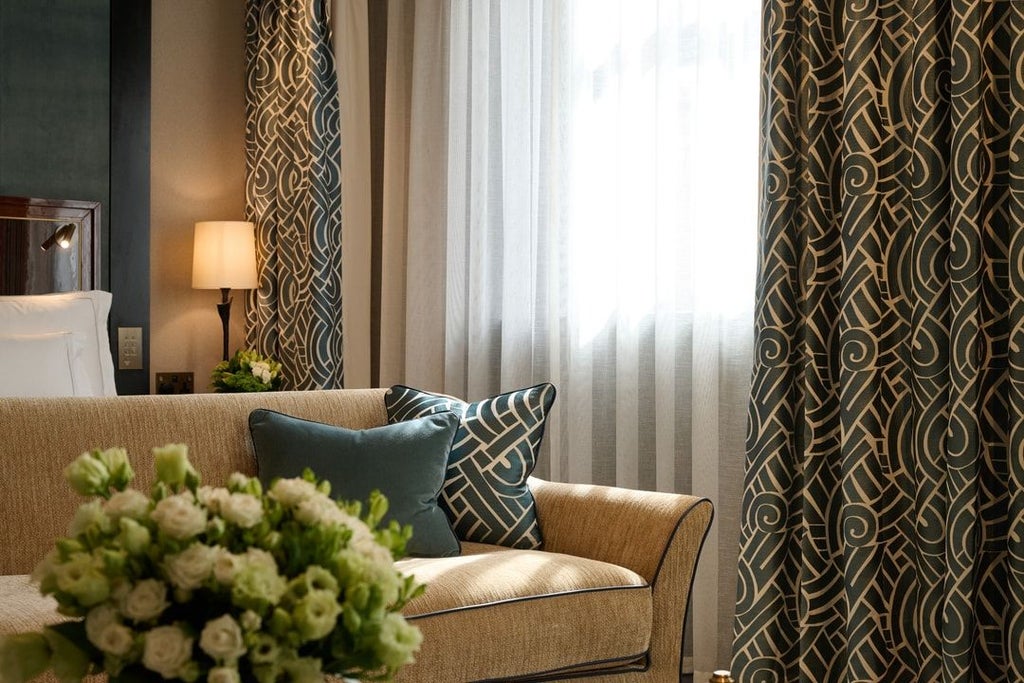 Luxurious studio suite at scenset Mayfair hotel with elegant king bed, plush cream furnishings, and sophisticated contemporary design against soft neutral palette