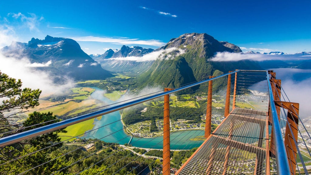 Panoramic mountain vista with luxurious wooden cabin, dramatic fjord landscape, snow-capped peaks, and golden sunset illuminating pristine Norwegian wilderness