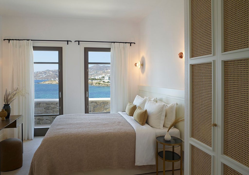 Luxurious three-bedroom villa overlooking Mykonos coastline, featuring private heated pool with panoramic azure Aegean Sea views and contemporary design