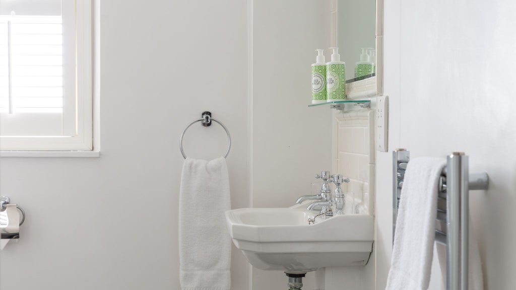 Modern, minimalist shower room with sleek glass enclosure, neutral stone tiles, and contemporary bathroom fixtures in a luxurious United Kingdom accommodation.