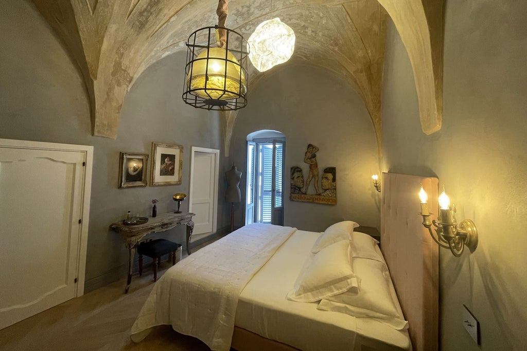 Elegant Deluxe Room with soft neutral tones, plush king bed, marble-accented bathroom, and expansive windows overlooking historic Italian architecture