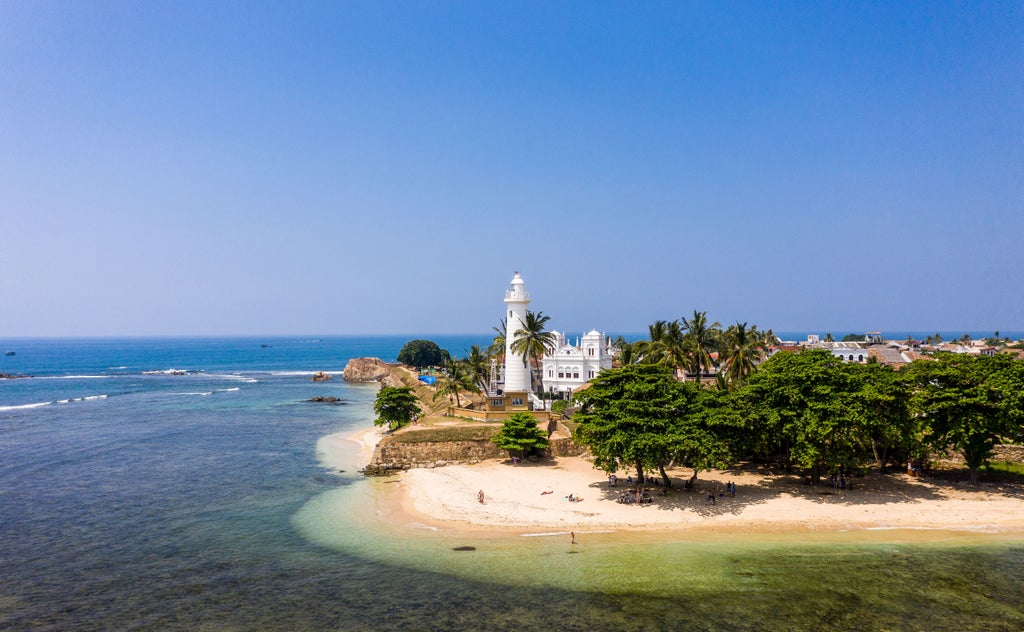 Colonial-style luxury hotel Amangalla with white columns and verandah, palm trees swaying against historic facade in Galle, Sri Lanka