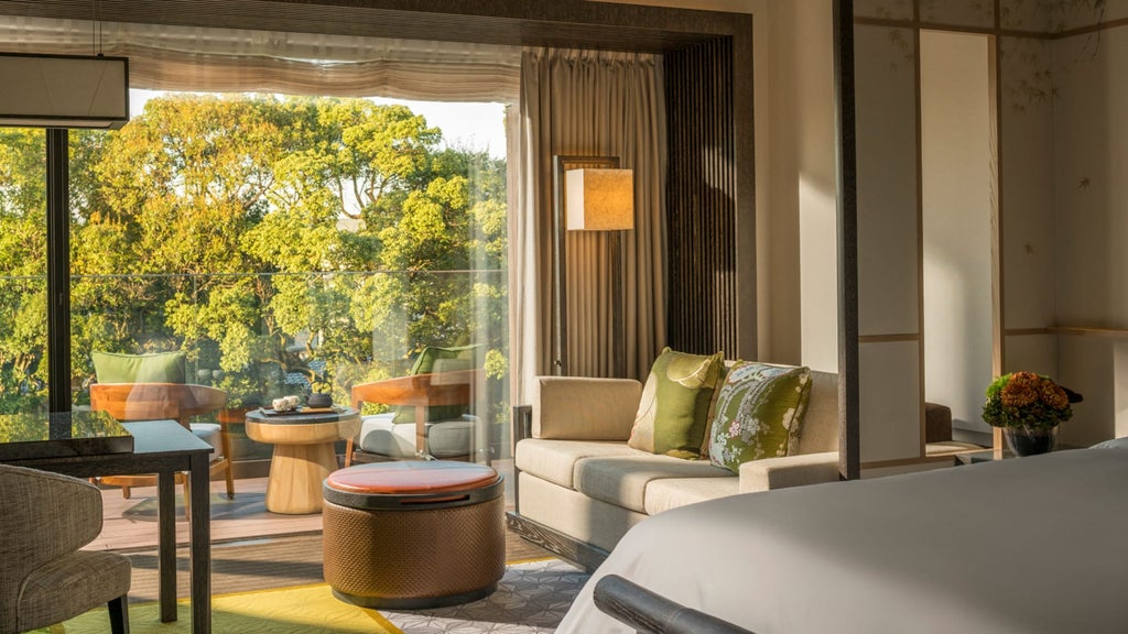 Elegant Japanese-inspired hotel room with tatami seating area, floor-to-ceiling windows, modern furnishings and city views at dusk