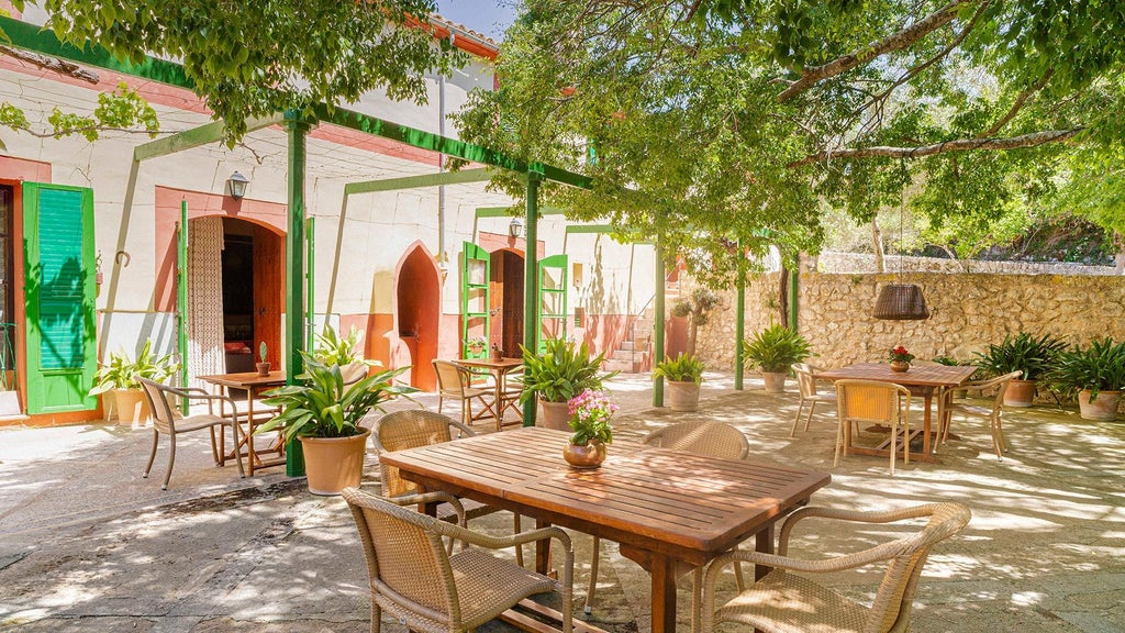 Rustic luxury finca nestled in scenic Mallorca countryside, featuring stone walls, lush gardens, and traditional Balearic architectural charm at sunset