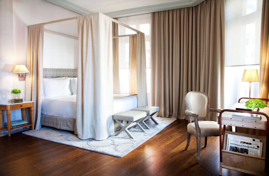 Elegant contemporary hotel room with warm neutral tones, plush bedding, modern furniture, and soft lighting at luxurious URSO Hotel & Spa in Madrid, Spain.