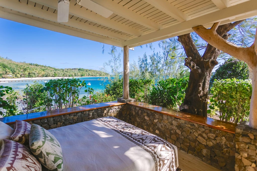 Luxurious Vonu Point Villa overlooking crystal-clear turquoise waters, with elegant wooden furnishings, plush white bedding, and panoramic ocean view in tropical Fiji