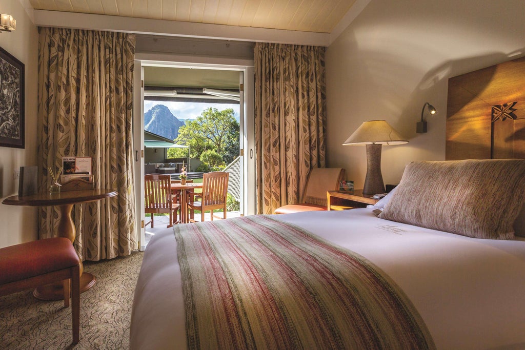 A luxurious mountain lodge nestled at the entrance of Machu Picchu, featuring stone walkways, lush gardens, and misty Andes peaks in background