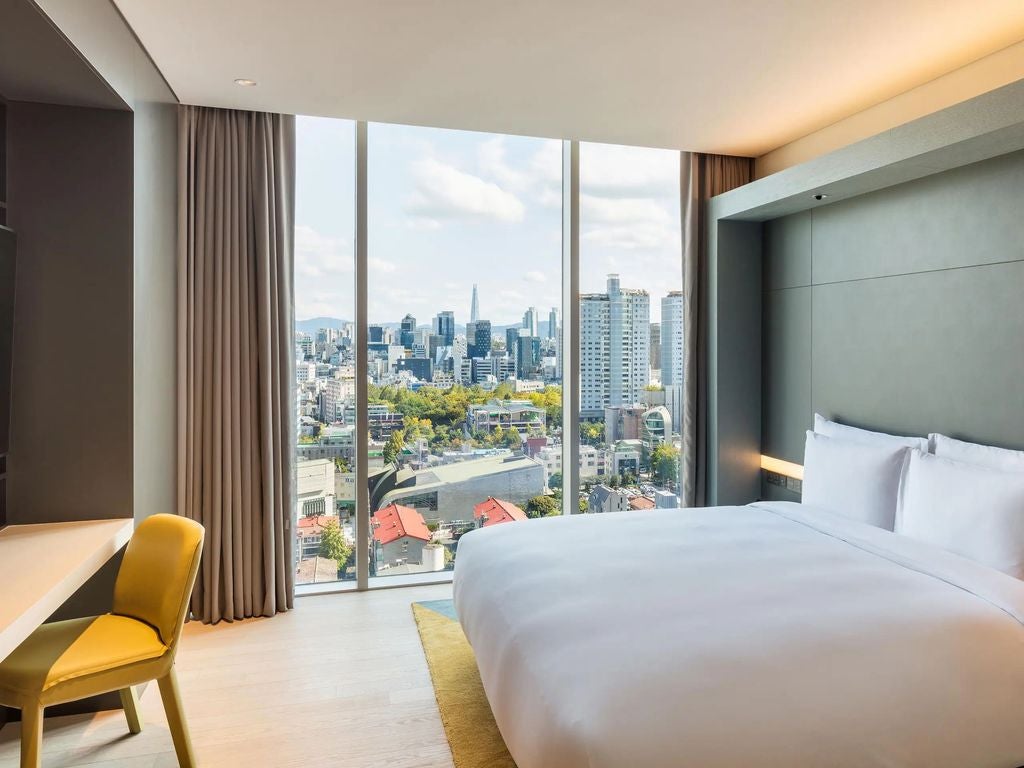 Modern luxury hotel exterior with glass facade, illuminated at night, featuring contemporary architecture in Seoul's upscale Gangnam district