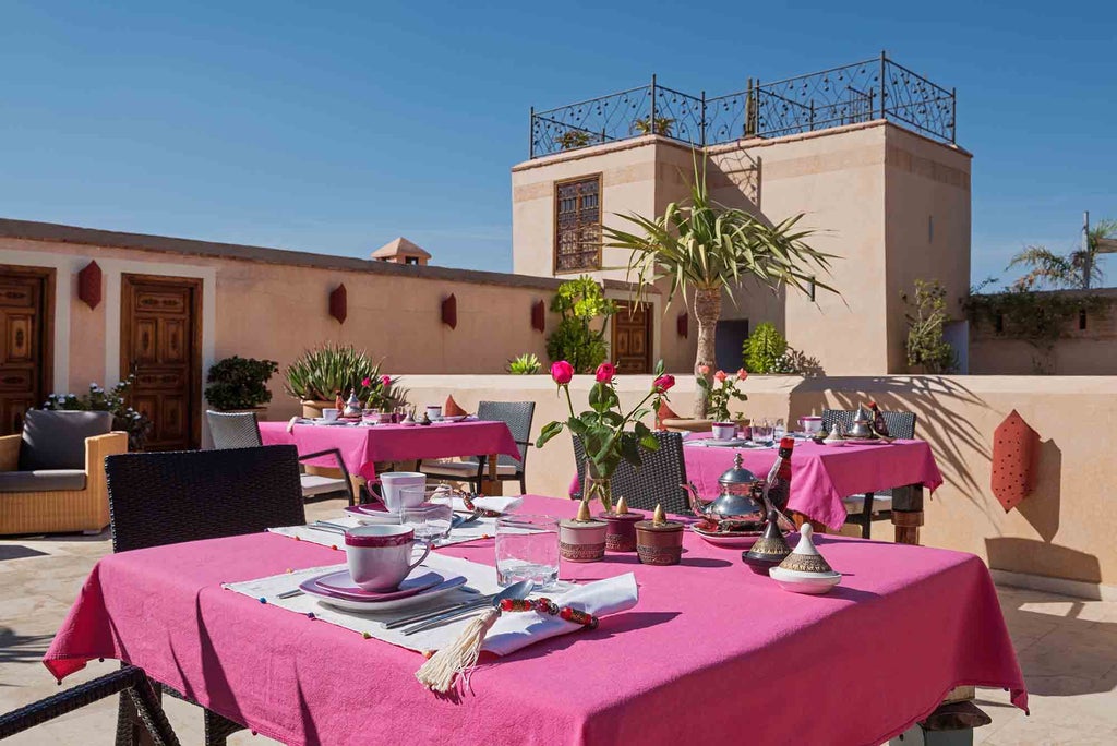 Historic Moroccan riad with ornate archways, traditional lanterns and intimate courtyard pool surrounded by elegant loungers and lush plants