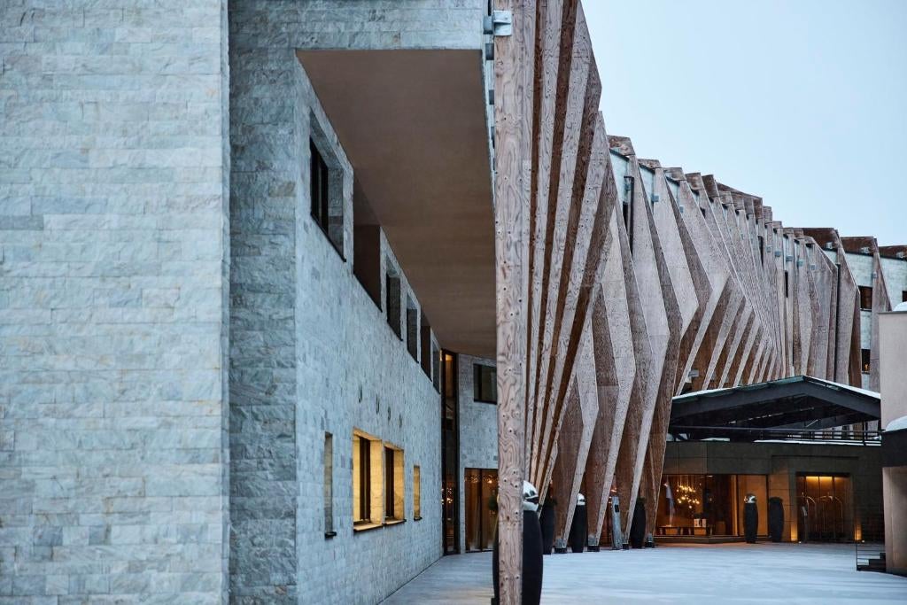 Modern alpine resort with glass facade nestled in snowy Dolomites mountains, featuring contemporary architecture and panoramic views