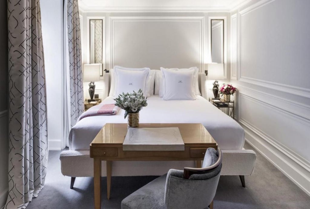 Elegant J.K. Junior suite in Paris with plush white bed, soft neutral tones, designer furnishings, and chic French-inspired luxury decor