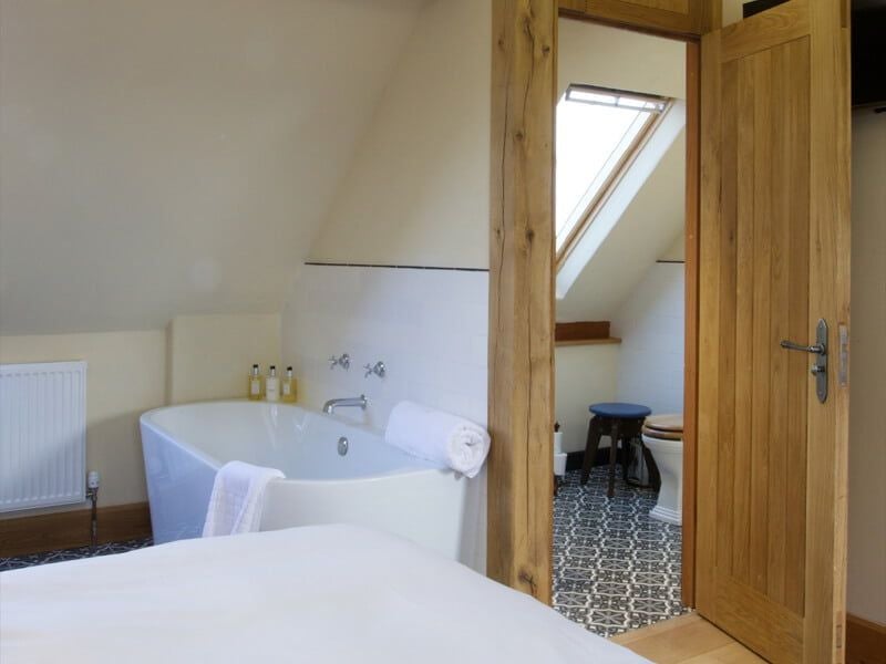 Elegant deluxe hotel room at Eckington Manor with crisp white linens, modern furnishings, and soft natural lighting illuminating warm wooden accents.