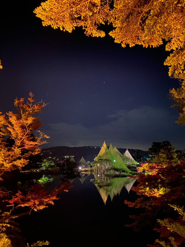 Traditional Japanese tea house beside serene garden pond in Kanazawa, featuring manicured bonsai and elegant wooden architecture