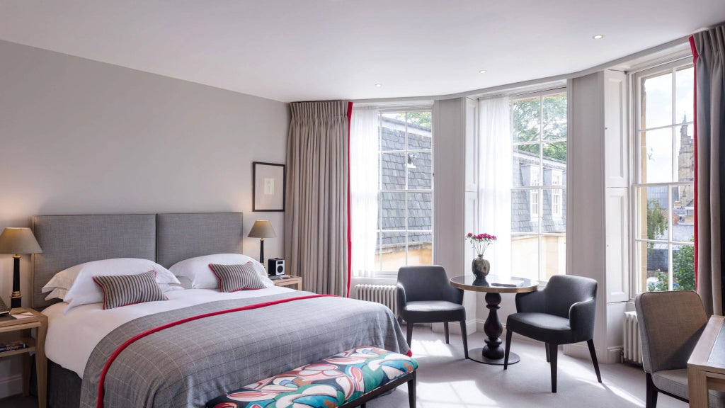 Elegant superior deluxe hotel room with classic British decor, featuring plush bedding, antique wooden furnishings, and refined architectural details from historic bank building.