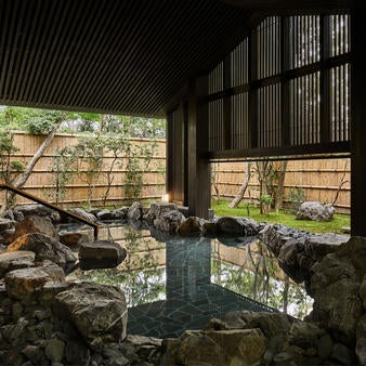 Minimalist Japanese luxury hotel nestled in serene forest, featuring sliding glass walls, wooden deck, and tranquil garden views