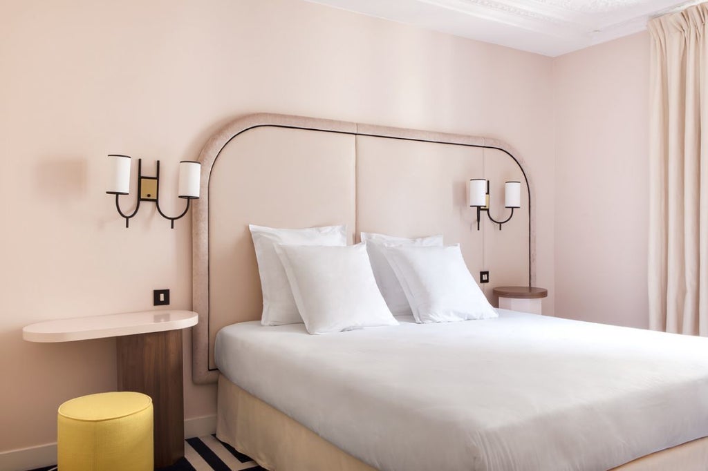 Cozy single room at Hôtel Bienvenue, featuring elegant white-painted walls, plush white bedding, and charming Parisian-style decorative elements