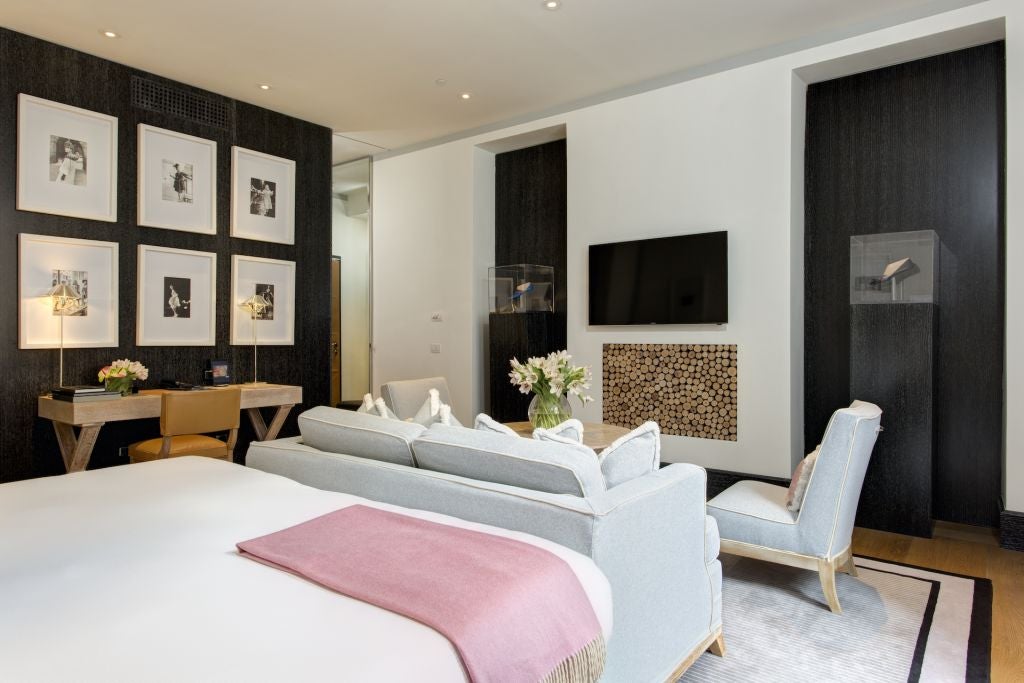 Elegant studio deluxe hotel room in Roma with modern luxe decor, soft neutral palette, plush bed, and expansive city view through large windows