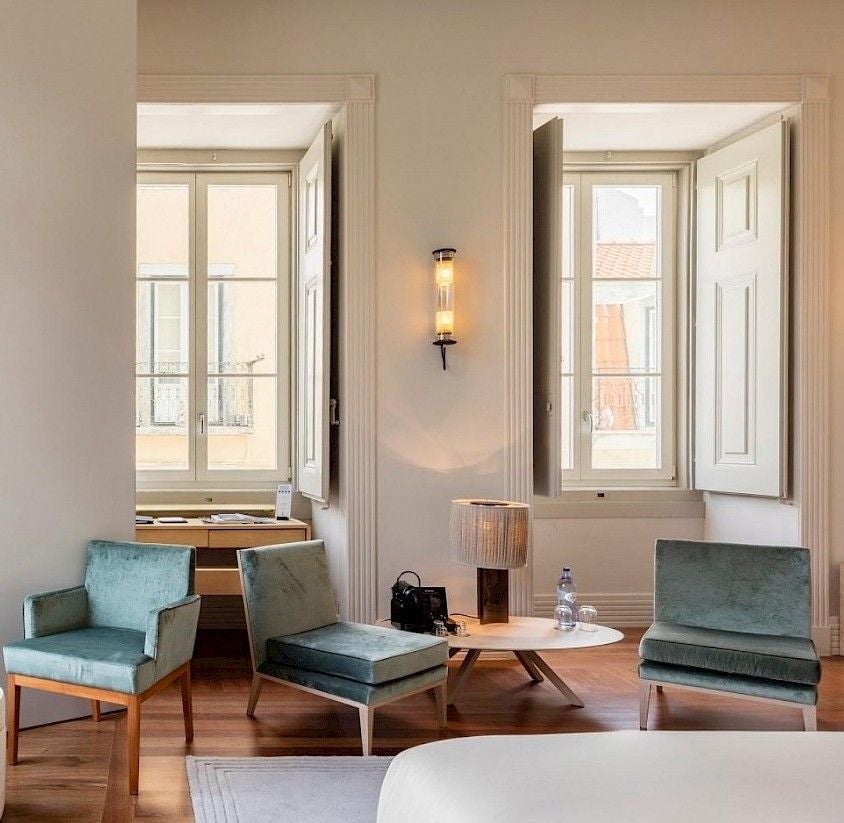 Elegant 18th century boutique hotel with ornate white facade, wrought-iron balconies and classic Portuguese blue tile accents in Lisbon