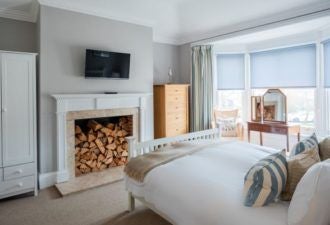 Elegant coastal bedroom in scenset hotel with crisp white linens, nautical-inspired decor, and expansive sea-view window overlooking Southwold's serene landscape