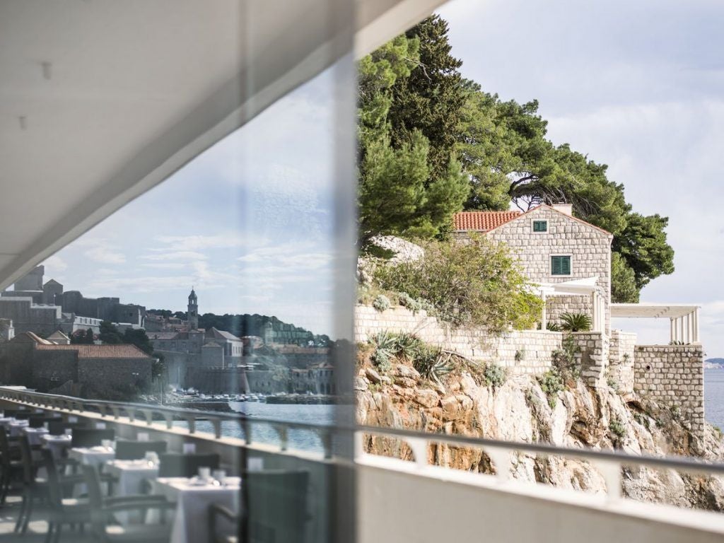 Elegant five-star beachfront hotel with classic stone architecture and palm trees overlooking the Adriatic Sea in Dubrovnik, Croatia