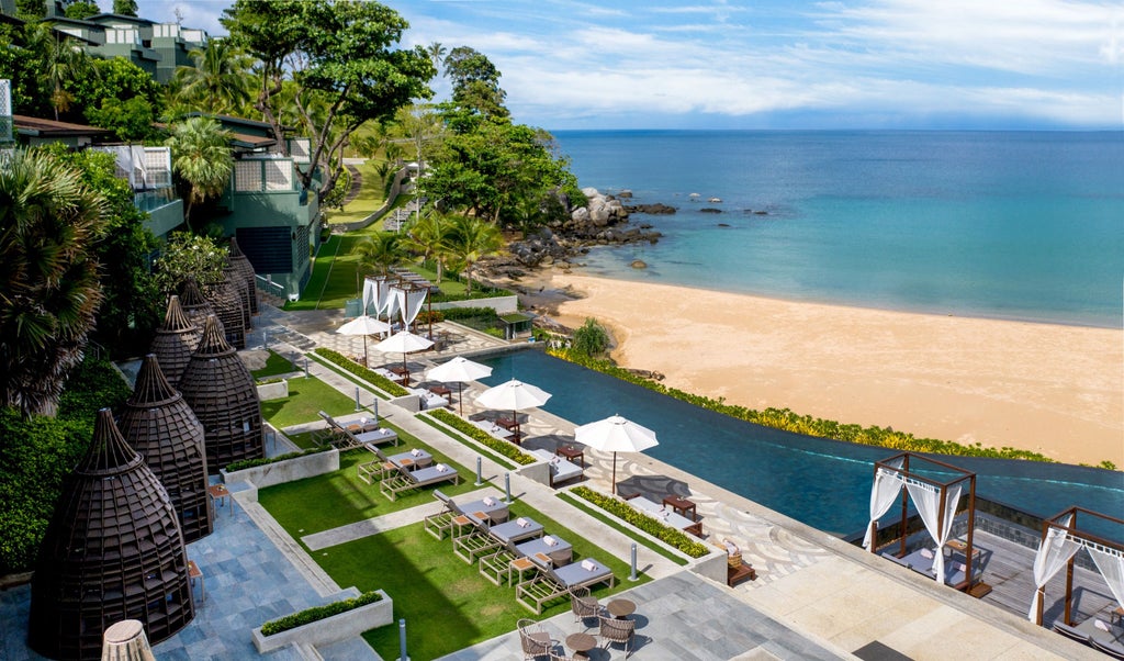 Luxurious infinity pool overlooking Kata Noi Beach at sunset, with modern sun loungers and palm trees framing the ocean view